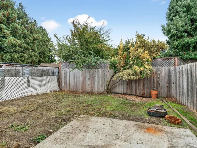 a view of a backyard with wooden fence and a bench