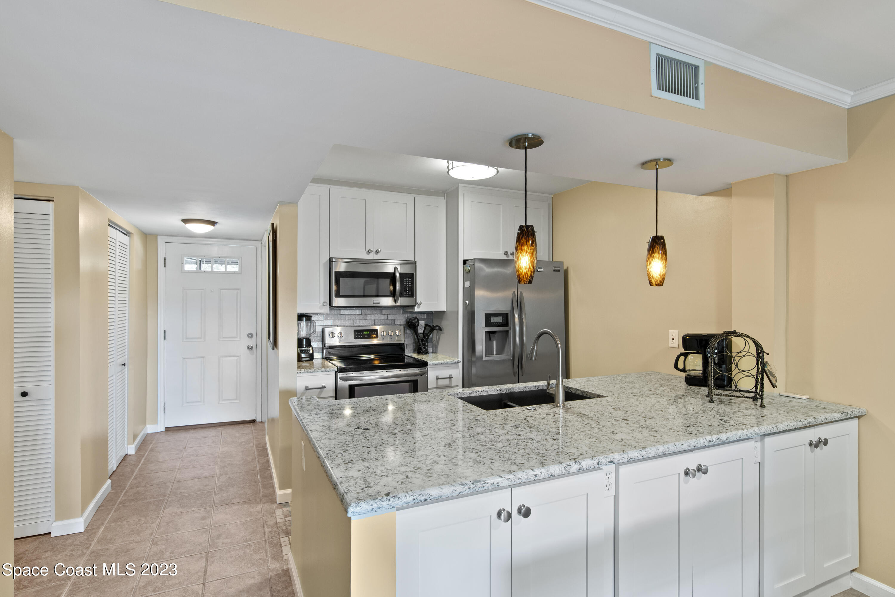 4150 Florida A1A, Unit 104 Vero Beach, FL 32963 - Photo 10 of 30 a kitchen with stainless steel appliances granite countertop a sink refrigerator and cabinets
