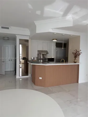 a living room with stainless steel appliances kitchen island granite countertop a refrigerator a sink a microwave and cabinets