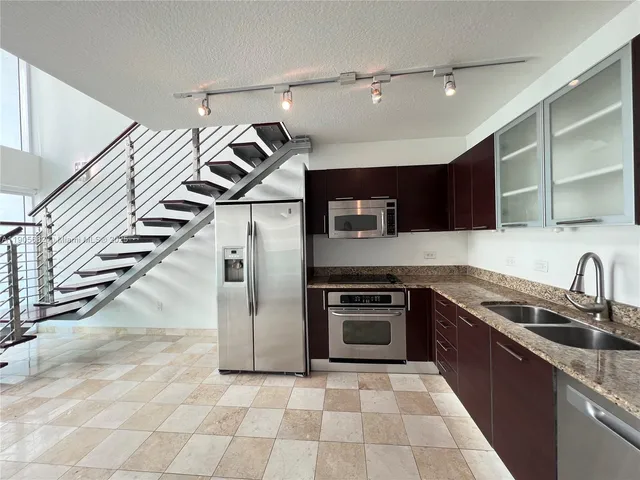a kitchen with granite countertop a sink and a stove top oven