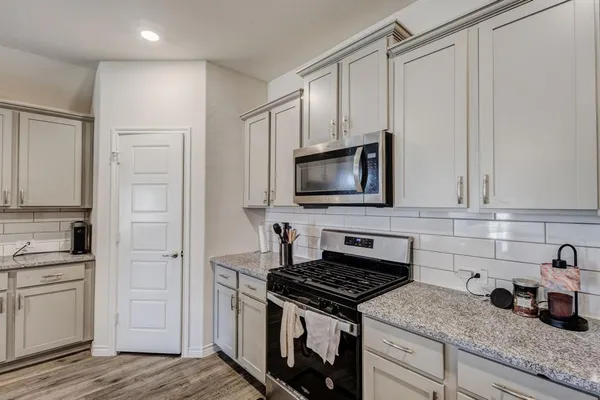 a kitchen with white cabinets and appliances