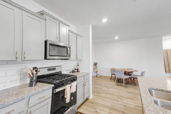 a kitchen with stainless steel appliances a stove a sink a microwave and wooden cabinets