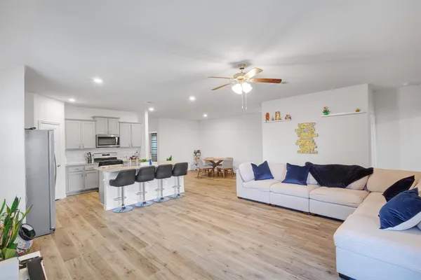 a living room with furniture kitchen view and a potted plant