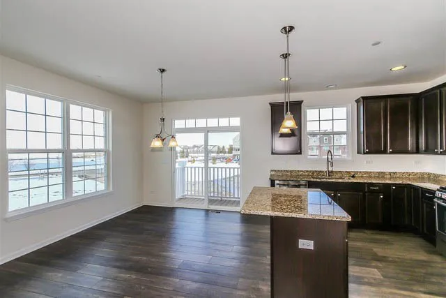 a kitchen with granite countertop a stove a sink dishwasher a refrigerator and white cabinets with wooden floor