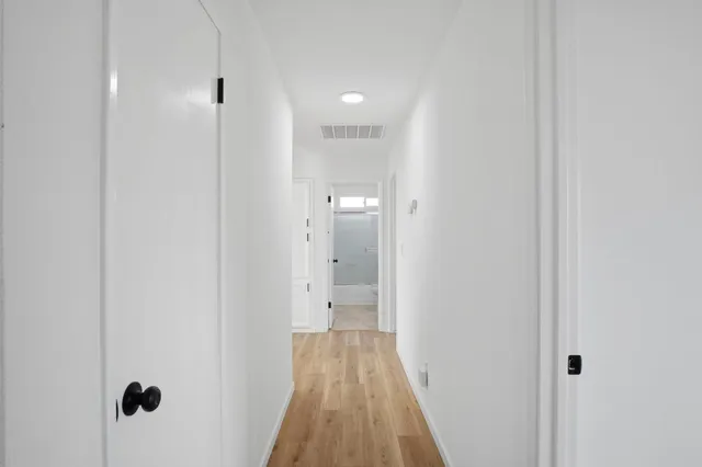 a view of a hallway with wooden floor and a bathroom
