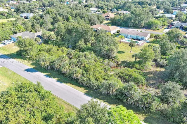 an aerial view of residential houses with outdoor space and trees all around