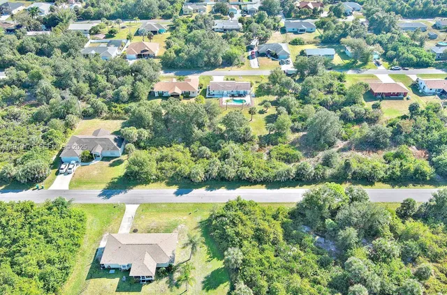 an aerial view of residential houses with outdoor space and trees all around