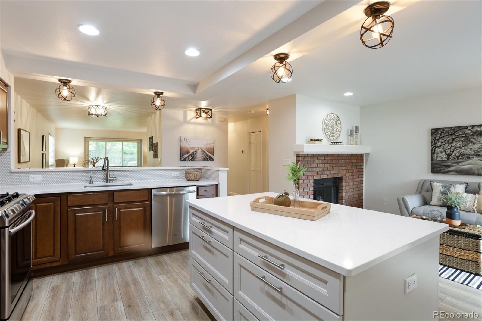 a large white kitchen with a stove a sink dishwasher and a fireplace with wooden floor