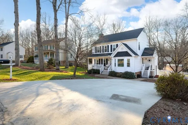 a view of a white house with a big yard and large trees