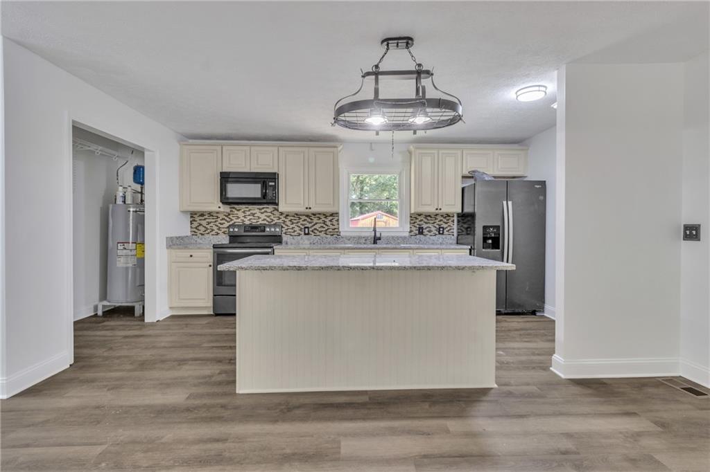 199 McKaskey Creek Road Southeast Cartersville, GA 30121 - Photo 8 of 34 a kitchen with stainless steel appliances granite countertop a refrigerator a stove a microwave oven with cabinets and wooden floor