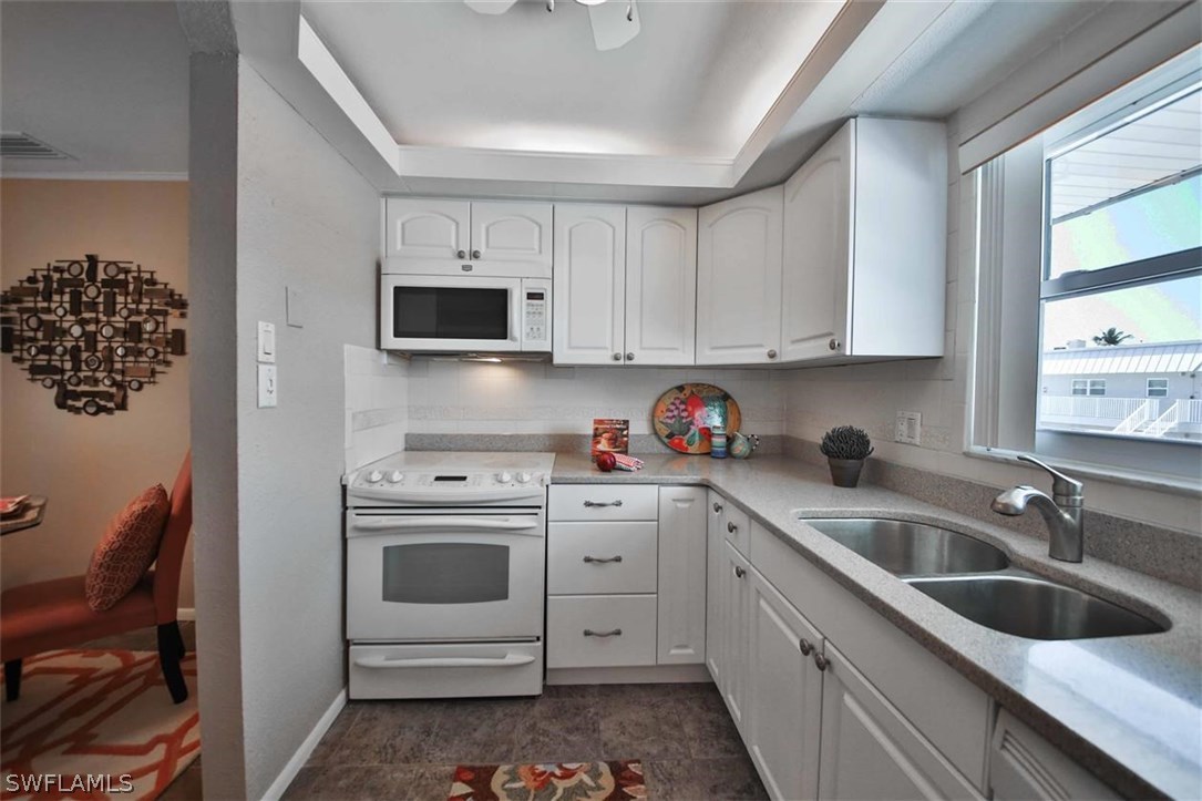 6777 Winkler Road, Unit 203 Fort Myers, FL 33919 - Photo 8 of 25 a kitchen with white cabinets and white appliances