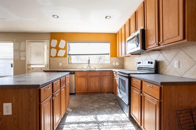 a kitchen with stainless steel appliances granite countertop a sink a stove cabinets counter space and a window