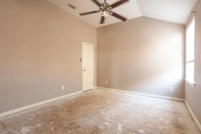 an empty room with a fan & a window