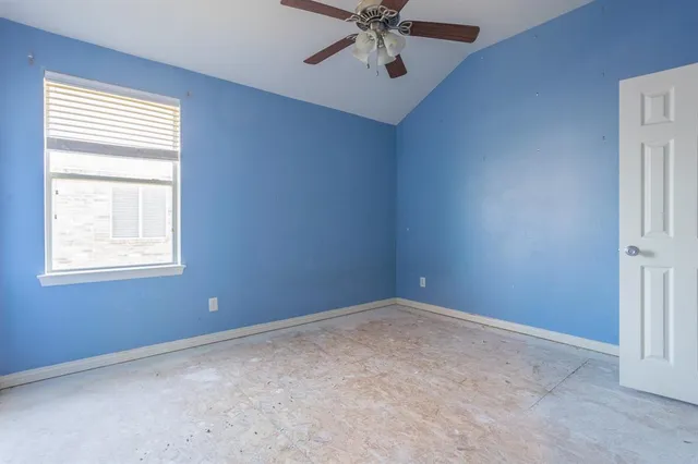 an empty room with a window and a fan