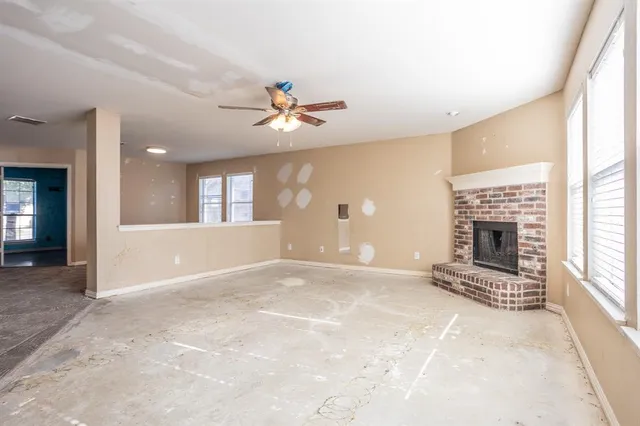 an empty room with windows and fireplace