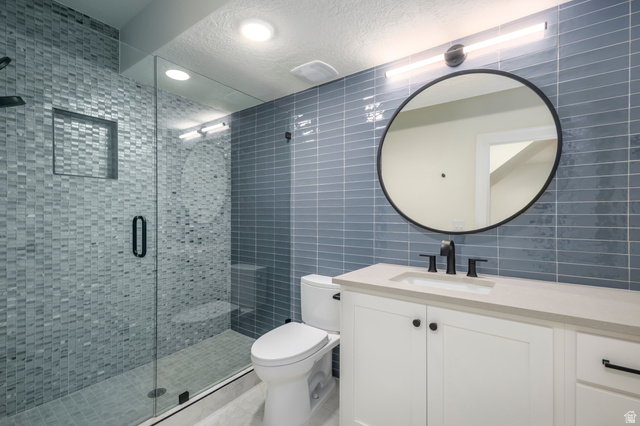 250 South Main Street, Unit 25 Alpine, UT 84004 - Photo 30 of 31 Full bathroom featuring tile walls, vanity, a shower stall, a textured ceiling, and decorative backsplash
