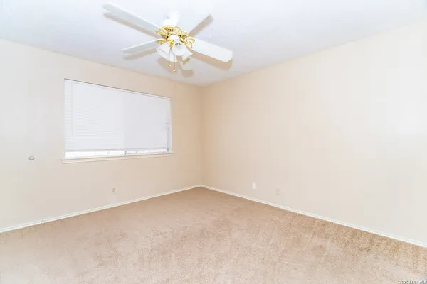 an empty room with a chandelier fan and windows