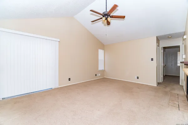 an empty room with ceiling fan and window