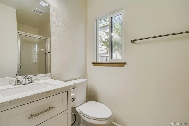 a bathroom with a granite countertop toilet a sink a mirror and a window