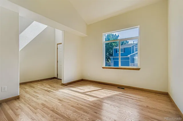 an empty room with wooden floor cabinet and windows