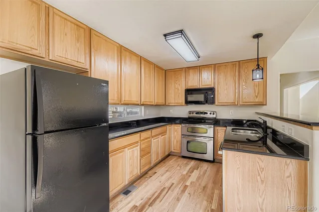 a kitchen with granite countertop a refrigerator stove top oven and sink
