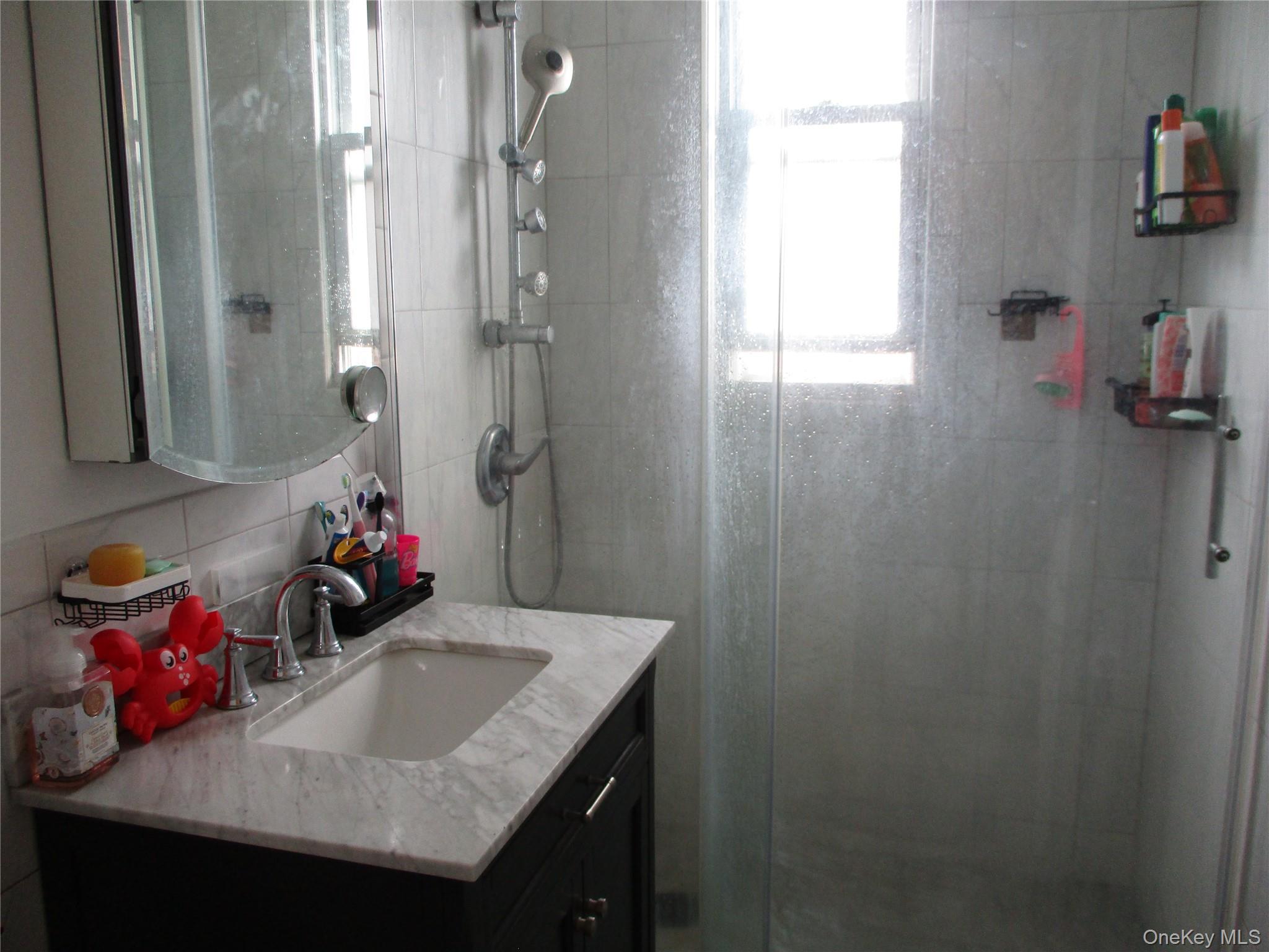 19 Acorn Road East Rockaway, NY 11518 - Photo 4 of 16 a bathroom with a granite countertop sink a mirror and shower