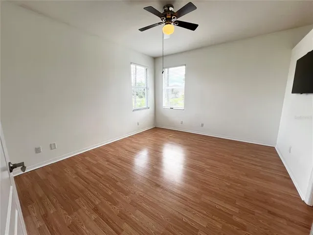 a view of empty room with wooden floor and fan