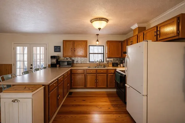 a kitchen with a refrigerator a sink and dishwasher with wooden floor