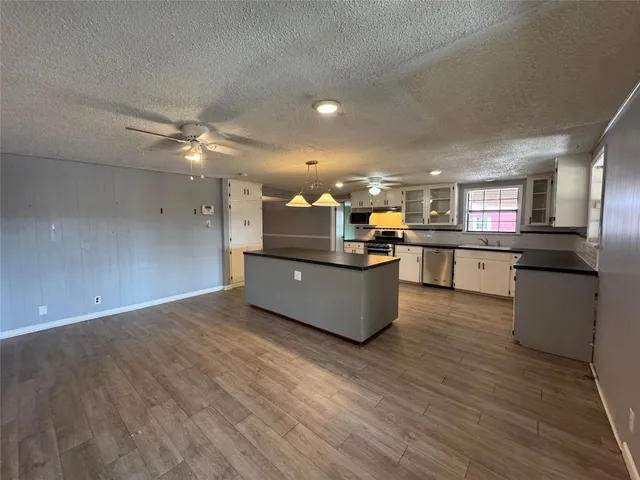 a kitchen with stainless steel appliances kitchen island granite countertop a stove top oven and a sink