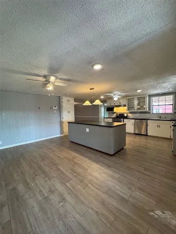 a living room with stainless steel appliances kitchen island granite countertop a sink and cabinets