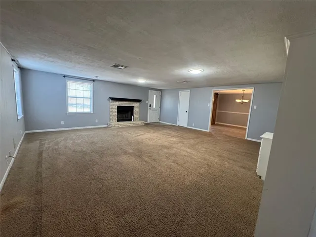 a view of an empty room with window and fireplace