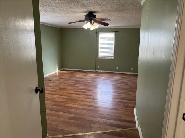 a view of an empty room with window and wooden floor