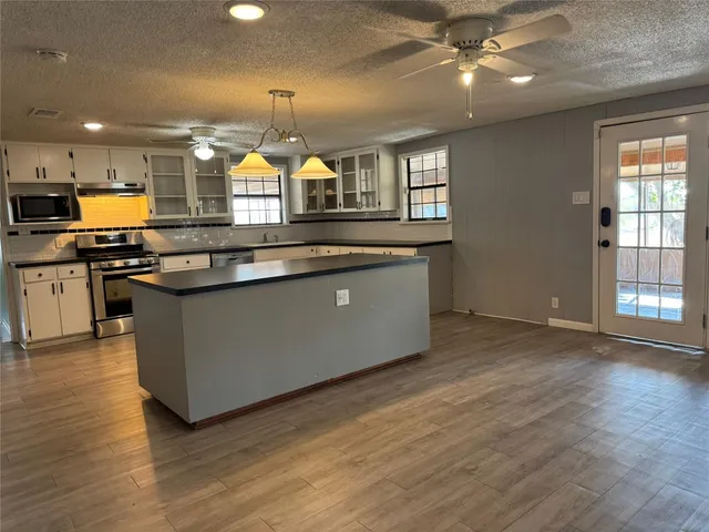 a kitchen with stainless steel appliances granite countertop a sink a stove and a wooden floors