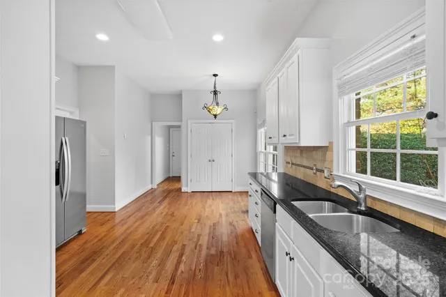 a kitchen that has a sink a stove and wooden floor