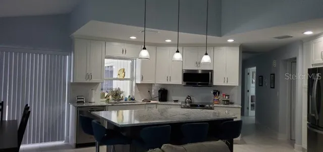 a kitchen with kitchen island granite countertop a sink a center island and cabinets