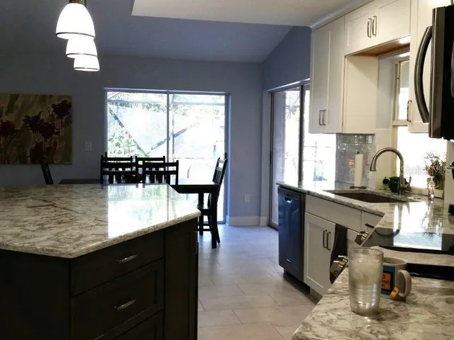 a kitchen with kitchen island granite countertop a sink a counter top space and living room area