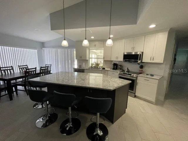 a kitchen with kitchen island granite countertop a sink a center island stainless steel appliances and cabinets
