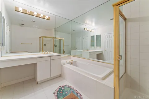 a bathroom with a tub a sink a large mirror and vanity