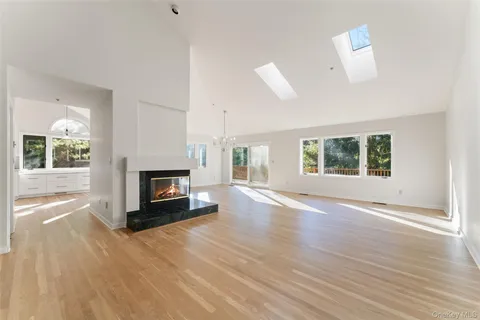 an empty room with windows fireplace and wooden floor