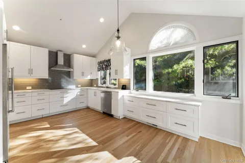 a large kitchen with kitchen island white cabinets and stainless steel appliances