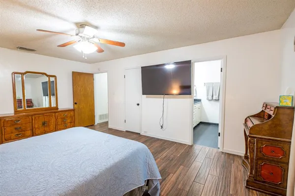 a bedroom with a bed and a flat tv screen on dresser