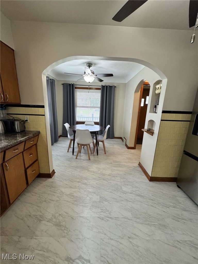 3712 Snow Road Cleveland, OH 44134 - Photo 6 of 40 Dining room with ceiling fan, arched walkways, light marble finish flooring, tile walls, and a wainscoted wall