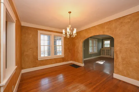 a view of an empty room with wooden floor and windows