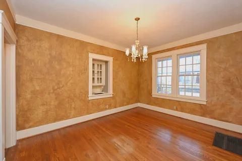 a view of an empty room with wooden floor and windows
