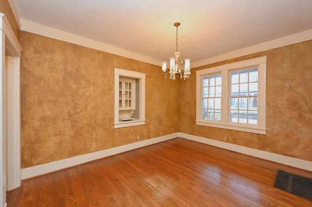 a view of an empty room with wooden floor and windows