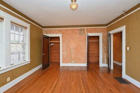 a view of an empty room with wooden floor and windows