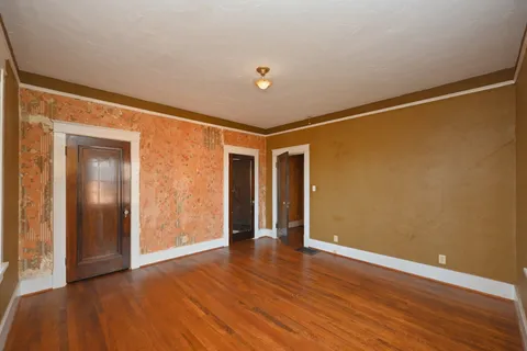 a view of an empty room with wooden floor and windows