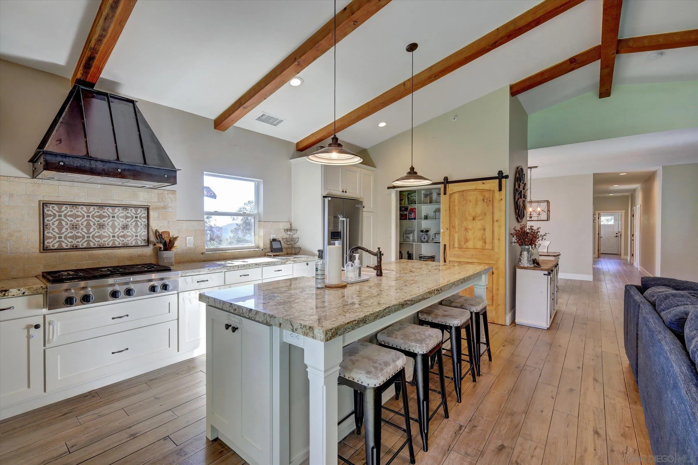11611 Rancho Heights Road Pala, CA 92059 - Photo 3 of 43 a kitchen with stainless steel appliances kitchen island granite countertop a table chairs in it and wooden floors