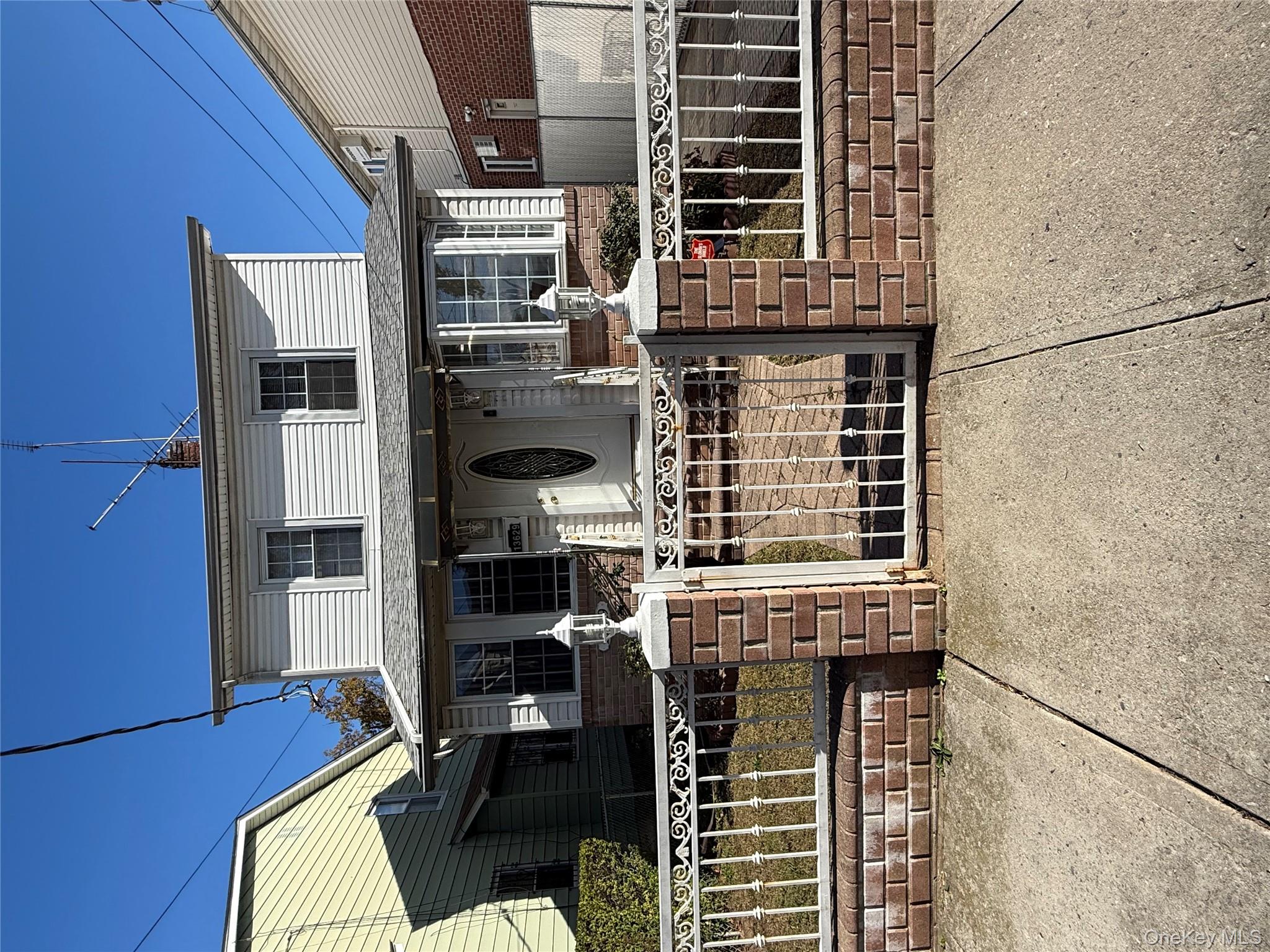 View of front of property with a gate, a fenced front yard, brick siding, and a chimney