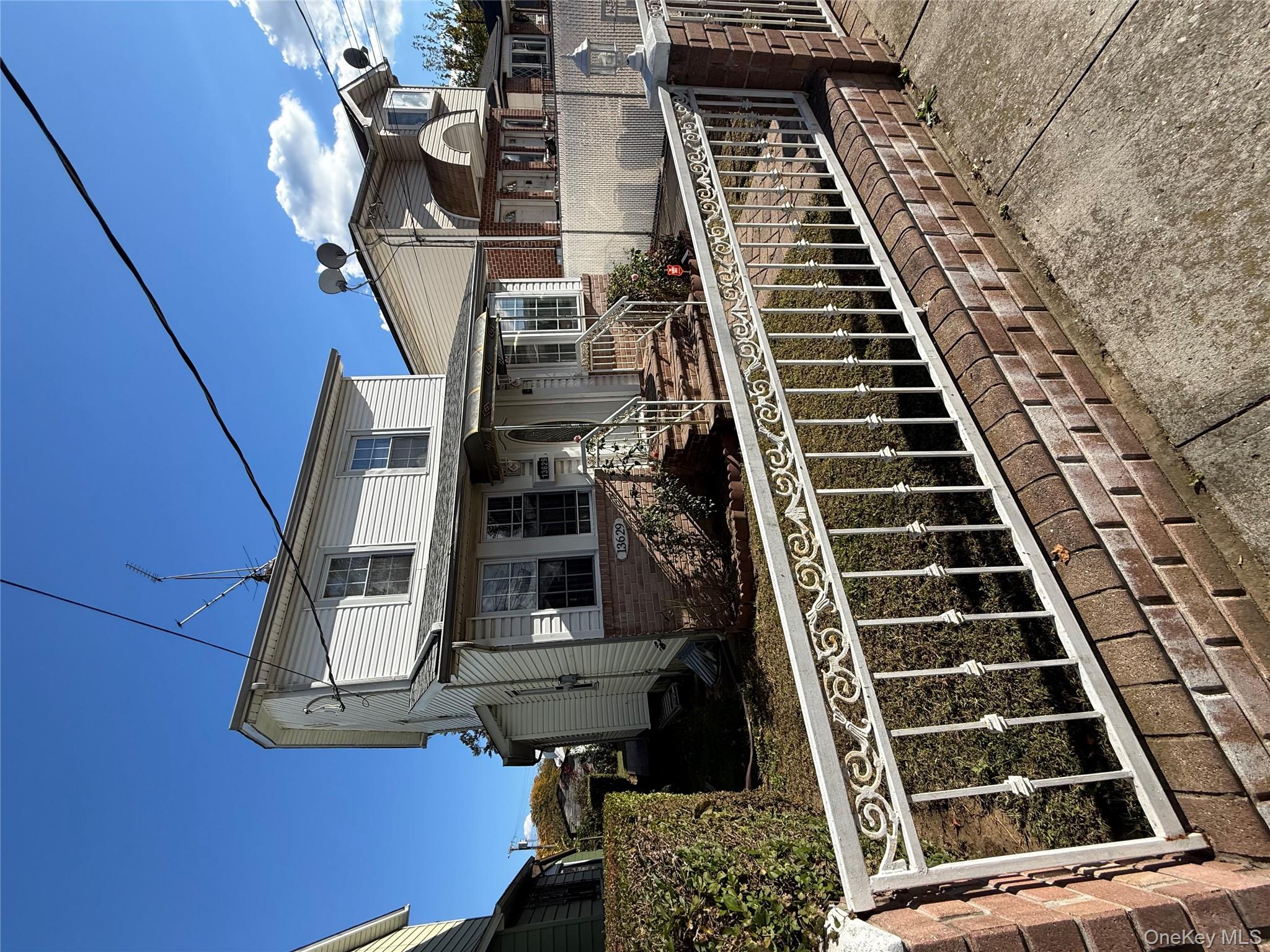 136-29 220th Place Queens, NY 11413 - Photo 2 of 45 View of front of property featuring a fenced front yard, brick siding, and a porch